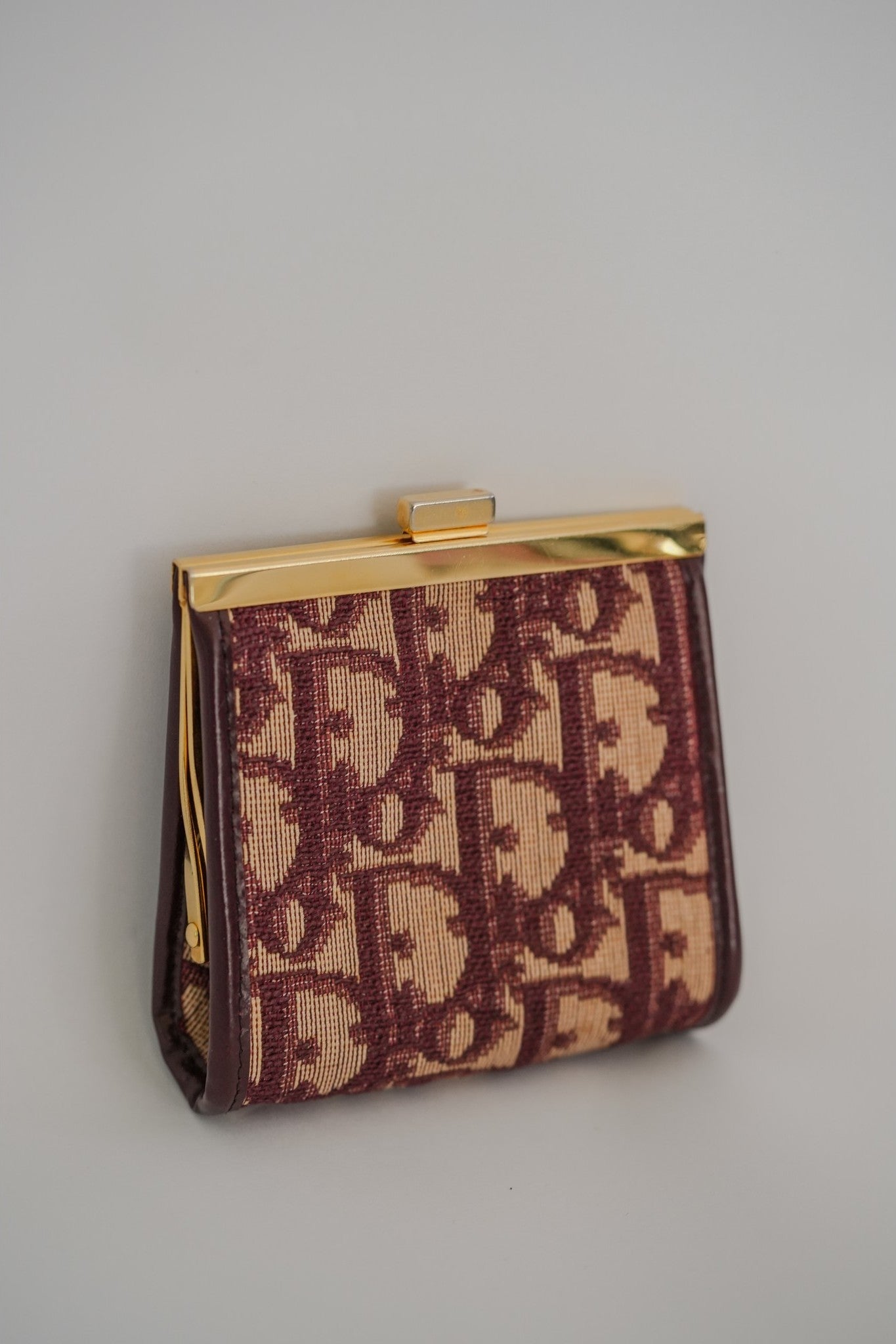 Vintage Christian Dior Trotter coin purse angled view showing gold kisslock frame and leather trim