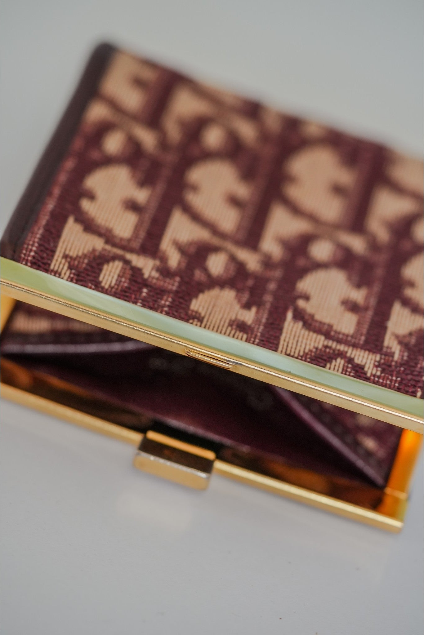 Christian Dior Trotter coin purse open showing gold kisslock mechanism and burgundy leather interior