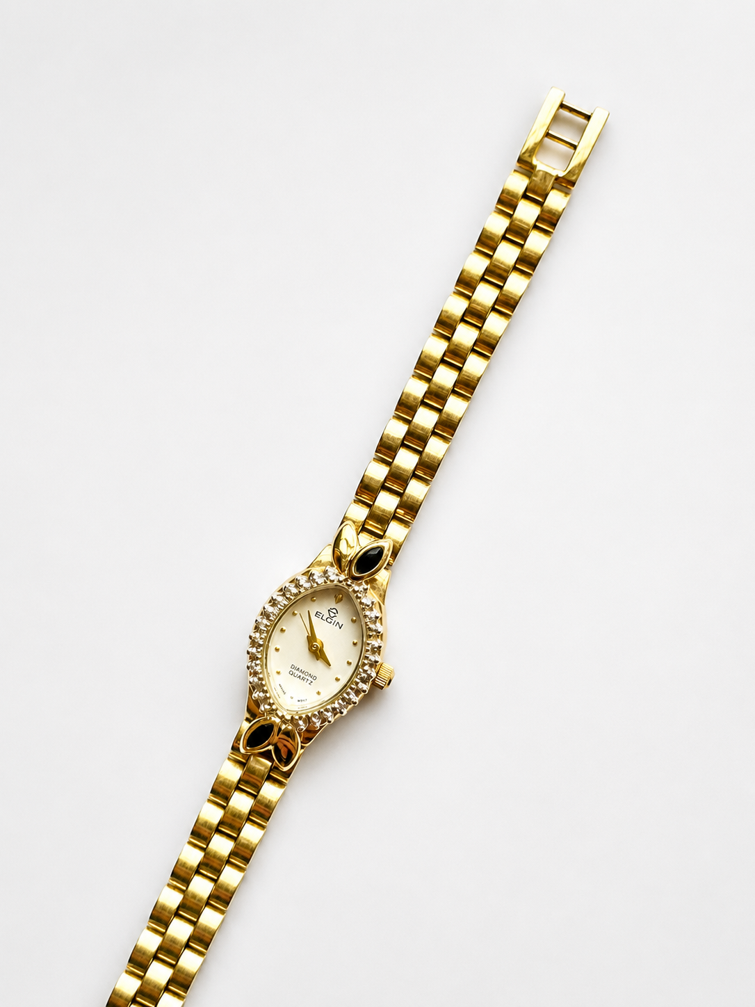Gold wristwatch with a decorative face on a white background