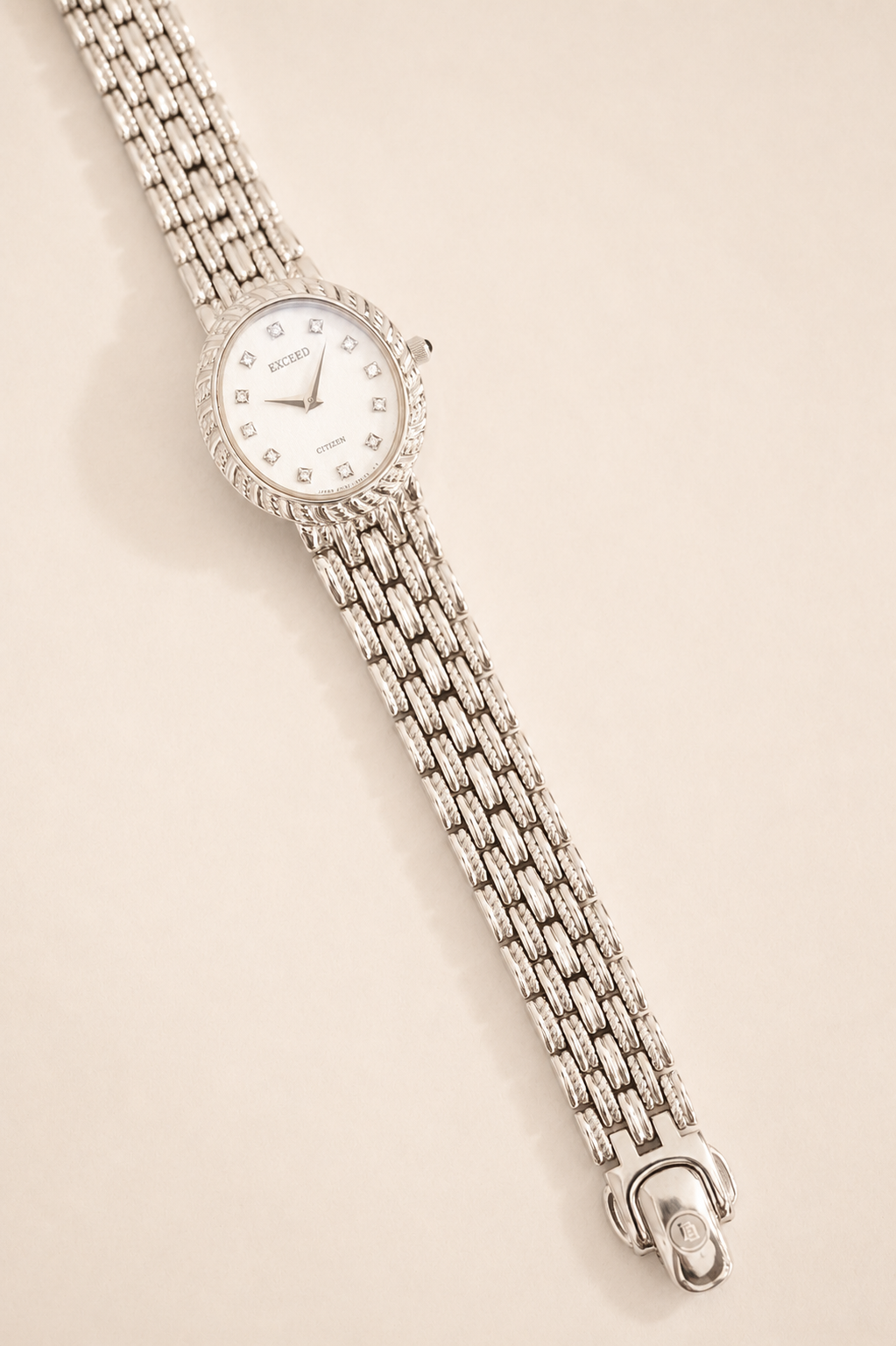 Silver watch with a chain strap on a beige background