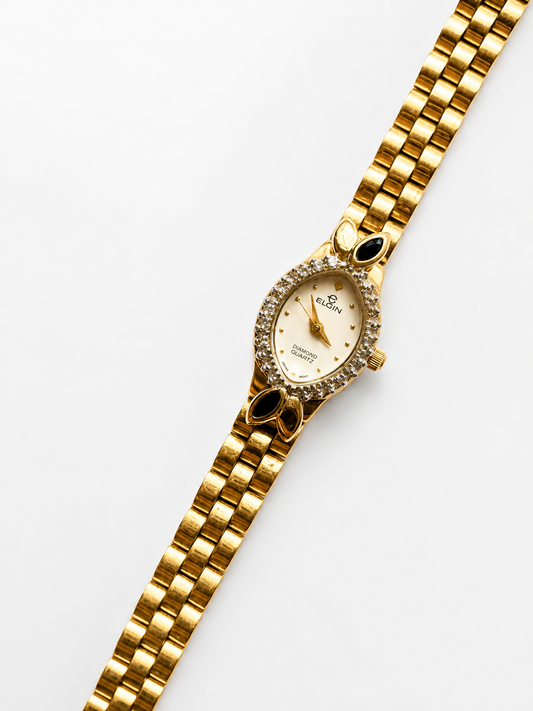 Gold wristwatch with a white dial on a light gray background