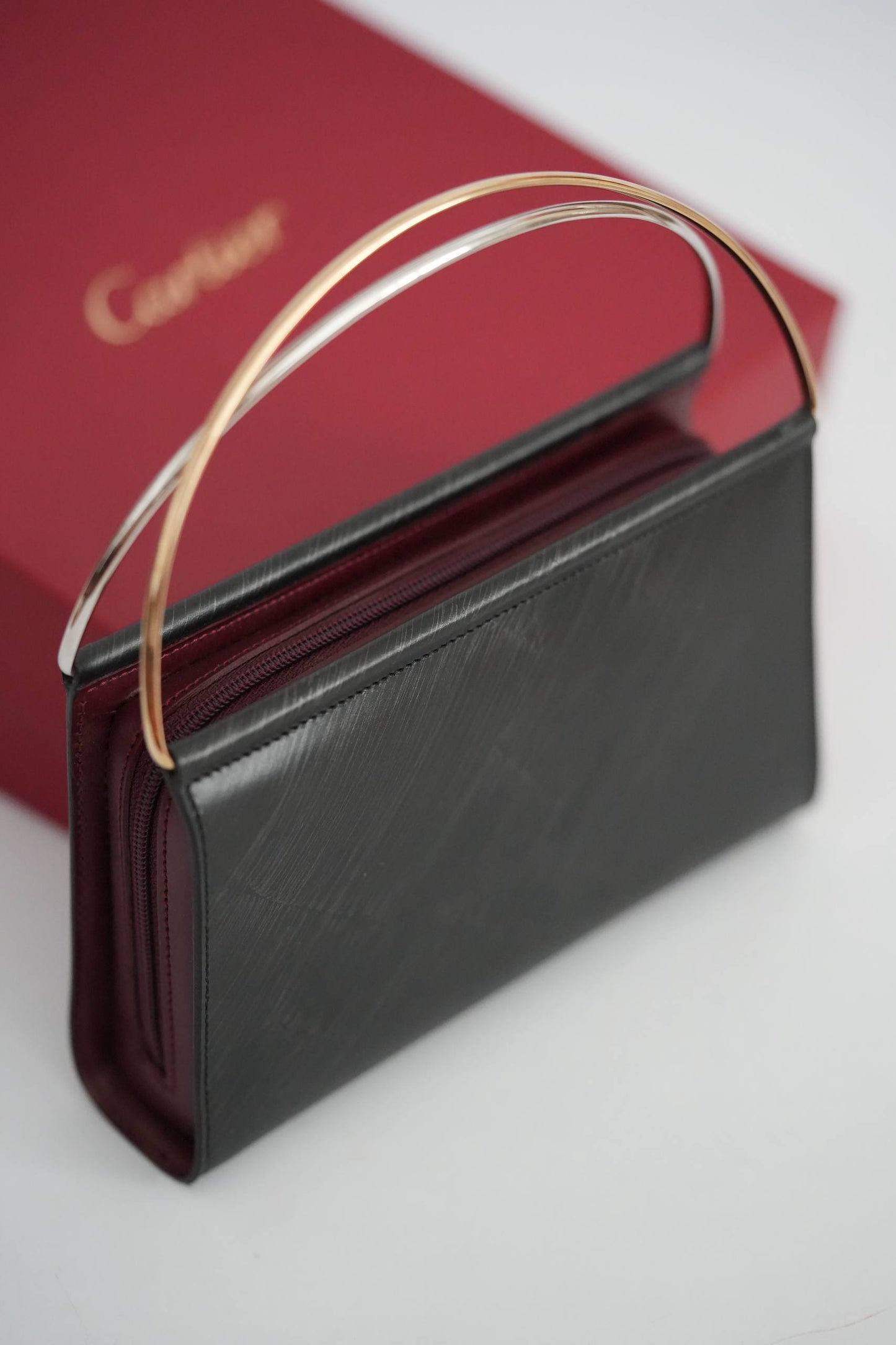 Cartier Trinity clutch bag front view black leather two-tone yellow gold white gold handle Cartier red box
