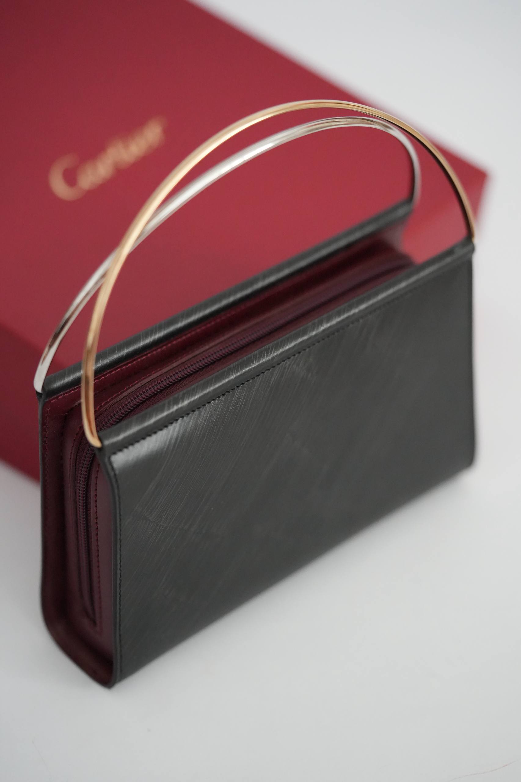 Cartier Trinity clutch bag front view black leather two-tone yellow gold white gold handle Cartier red box