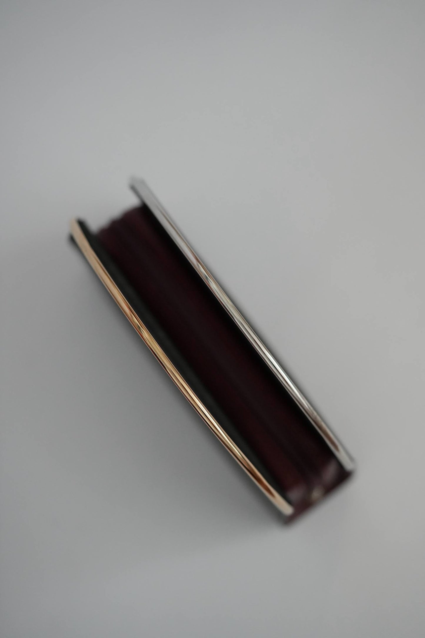 Cartier Trinity clutch top-down view two-tone gold arched handle yellow gold white gold grey background